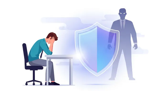 책상 앞에 앉아 힘들어하는 직장인 옆에 보호막이 있는 직장 내 괴롭힘 보호조치 개념 일러스트